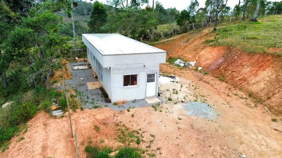 Vista aérea da casa construída no terreno, com telhado metálico e esquadrias instaladas